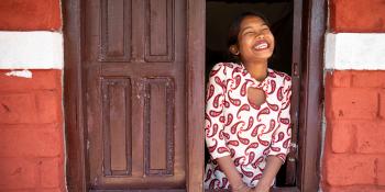 A woman smiling in a window.