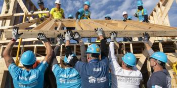 CEO Build attendees volunteer together as they lift a wooden frame at the Carter Work Project build site, October 2024. 