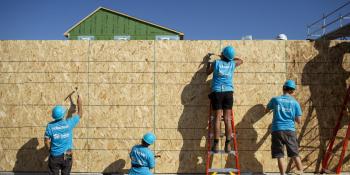 Four volunteers working on a wall with their backs to the camera. 