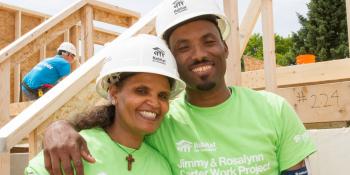 Habitat homeowners Teberh and Alem pose on build site wearing hard hats
