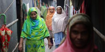 Several women in Bangladesh walk through an alleyway together.