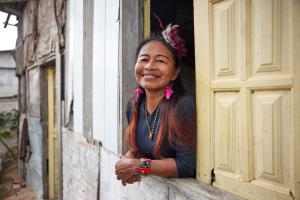 A woman smiles from a window with yellow panes.