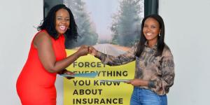 Two women bump fists in front of insurance poster