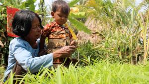 Elderly woman showing her young grandchild how to work in the garden.