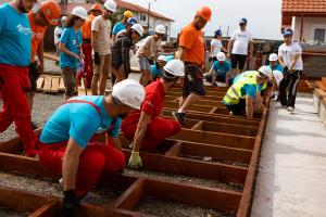 Volunteers lifting a wall from the ground on build site