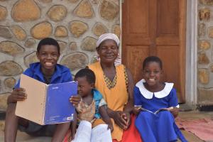 A woman and three children sit outside their home smiling