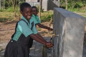 School children washing their hands at a hand washing station in school