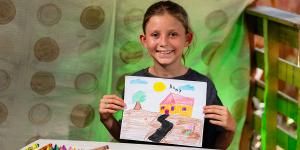 Una niña muestra el dibujo de su casa