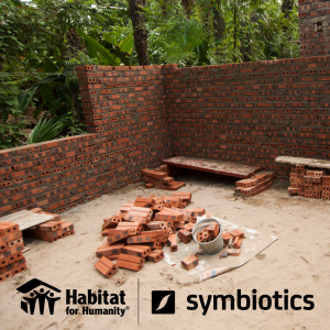 Partially built brick wall with a logo lockup of Habitat for Humanity and Symbiotics.