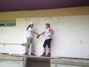 Two volunteers shaking hands on a construction site in hard hats