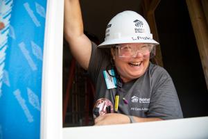 Woman in a hardhat smiling while volunteering on a build site