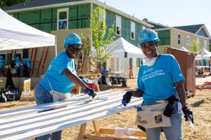 Volunteers painting trim on the site of the Carter Work Project. Behind them, the houses are in various states of completion.