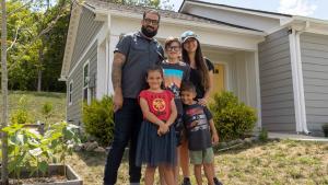 Neil, Erica and their three kids hugging outside their home.