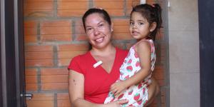 Madre sonríe mientras sostiene a su hija pequeña en el baño de su hogar, un espacio seguro y digno que refleja bienestar y nuevas oportunidades para la familia