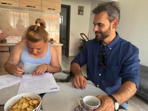 CEO of Habitat for Humanity Romania sitting next to Mihaela, signing her house form