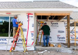 Two men work on a construction site of an unfinished house.