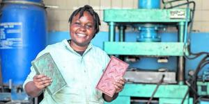 Woman holding up two recycled plastic bricks