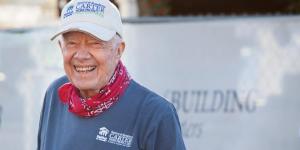 President Carter smiling wearing a red bandana, a white Habitat hat and a blue Habitat shirt.