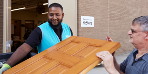 ReStore staff member helping man carry donated door