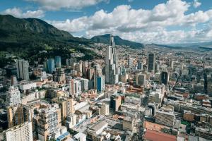 Urban Bogota, Columbia, with highrise buildings against a backdrop of mountains and a blue sky full of fluffy, white clouds.