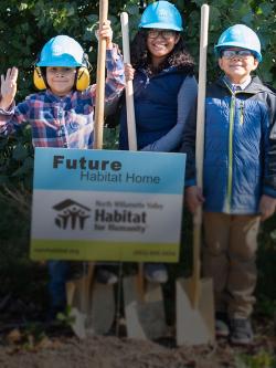 Three kids in hard hats next to sign that says "Future Habitat home"