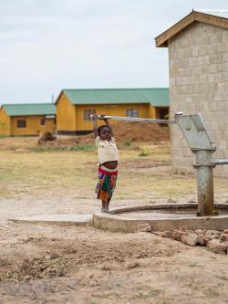 Young child pumping water from a well in Zambia.