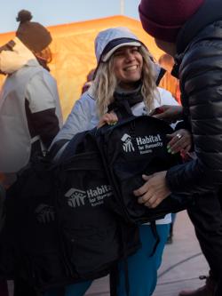 A woman receiving a Habitat backpack with supplies.