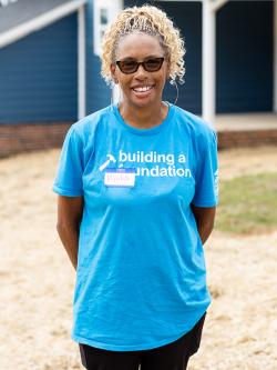 Woman smiling in a Habitat shirt that says "Building a foundation"