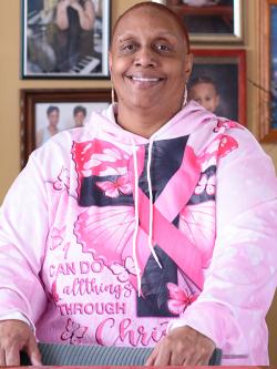 Portrait of woman smiling in front of framed family photos in her home.