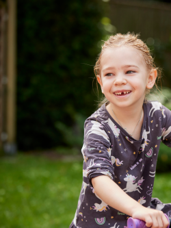 Young girl smiles while riding a bicycle.