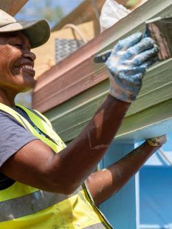 Fijian community member painting an exterior wall