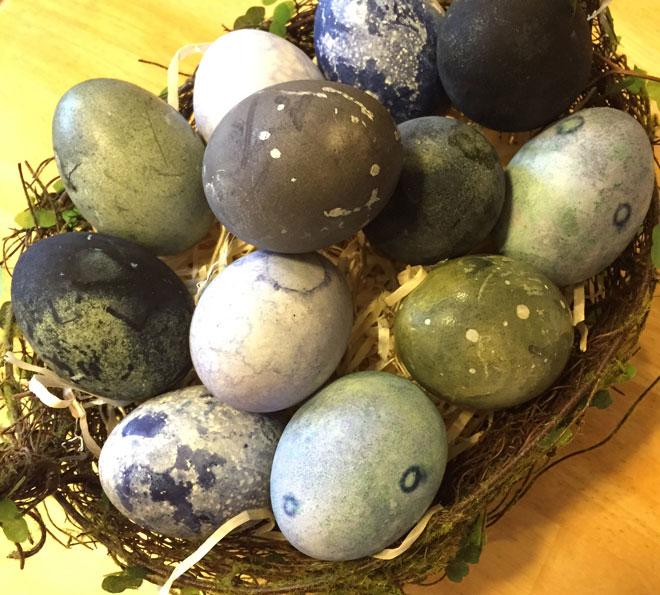 A basket of speckled eggs in blue and green colors.