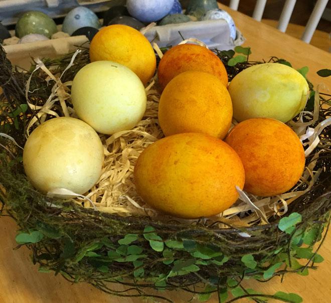 A basket of yellow and orange dyed eggs.