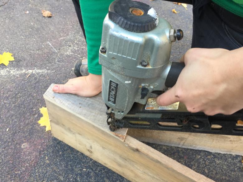 Scrap piece of pallet wood secures the Christmas tree frame