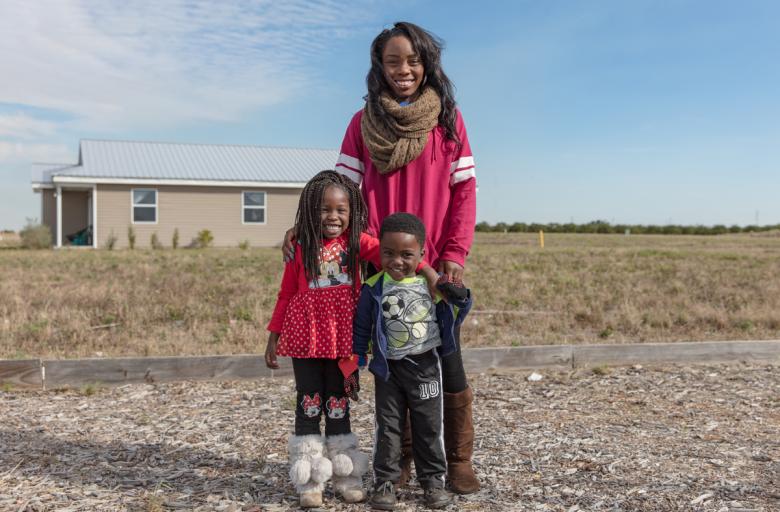 homeowner family mother and two children standing and smiling.