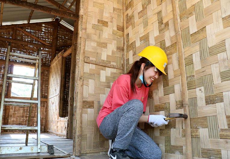 A Japanese volunteer putting up bamboo wall panel at Asia Build, Myanmar.