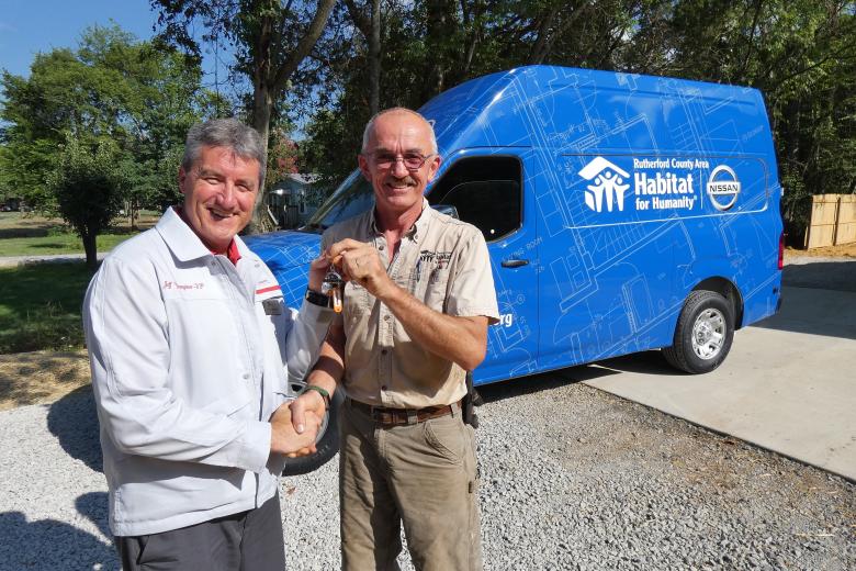 Nissan employee giving van keys to Habitat employee.