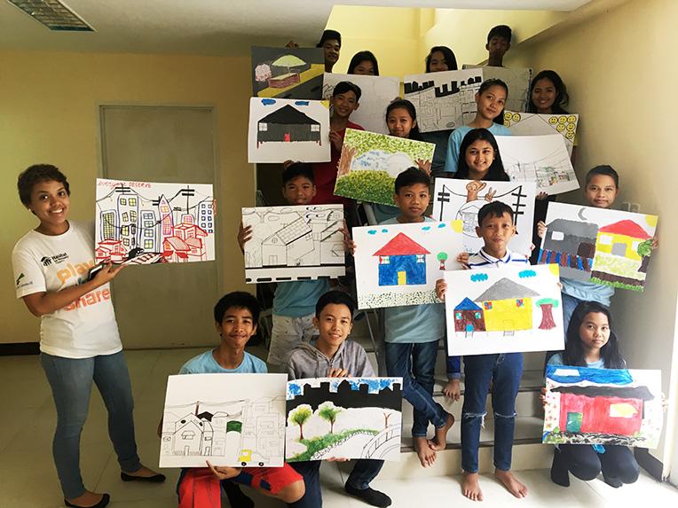 Children of Habitat homeowners in Bistekville, Philippines, showing their artwork on decent housing.