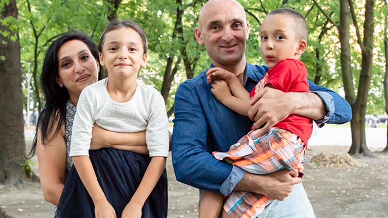 Photo: parents holding their two children in their arms.