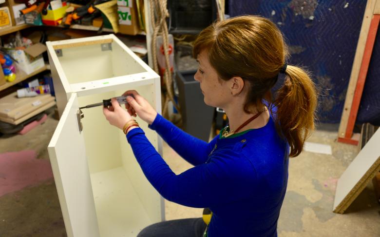 Theresa removes the hinges from the cabinet.