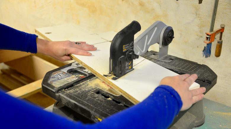 Theresa cuts the shapes with a tabletop saw.