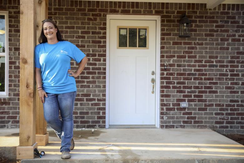 Kellie Lloyd stands on the porch of a Habitat home.