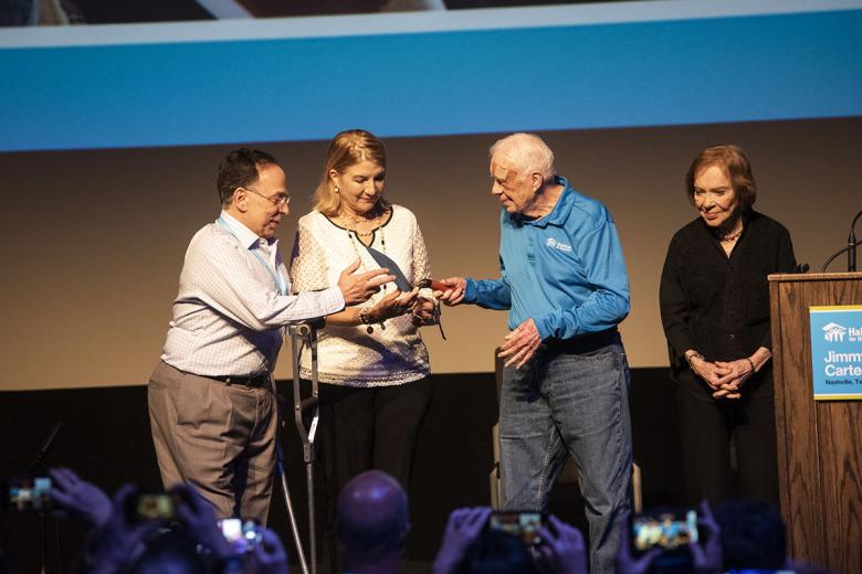 Former President Jimmy Carter passes a ceremonial trowel to Cesarina Fabián.