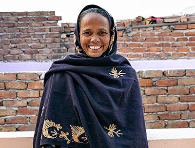 Reshma smiling in front of her brick Habitat home.
