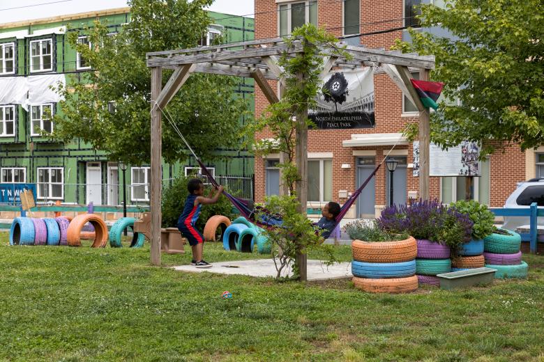 Two children play on a hammock swing in a Philadelphia park.