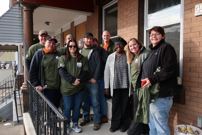 A team of volunteers stand in front of the home, smiling.