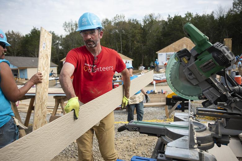 Man in a Wells Fargo volunteers shirt working on Habitat build site. 