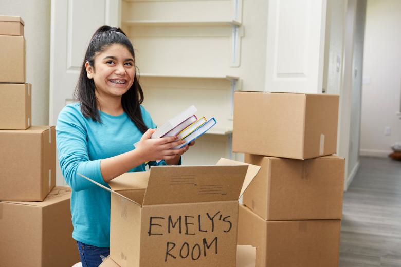 A teenage girl unpacks moving boxes.