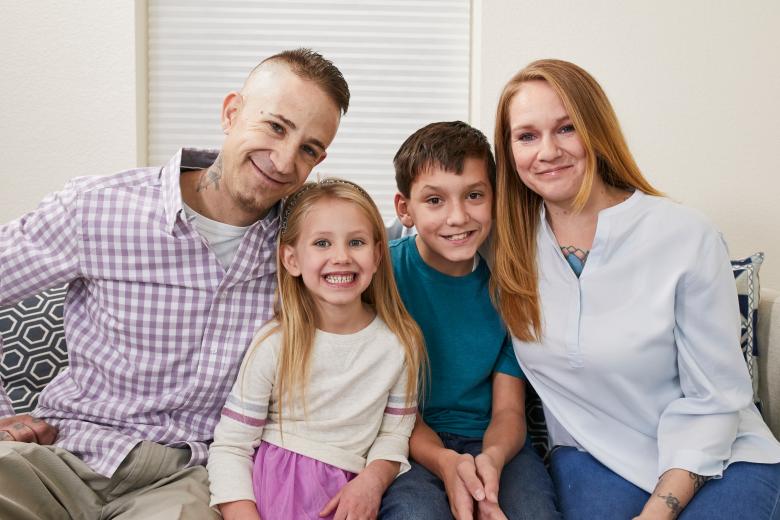 Parents and their son and daughter pose for a family portrait on the living room couch.