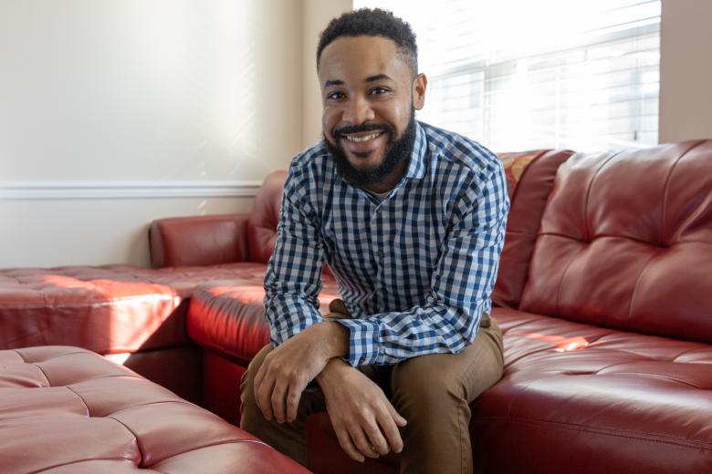 Bobby sits on his couch smiling.